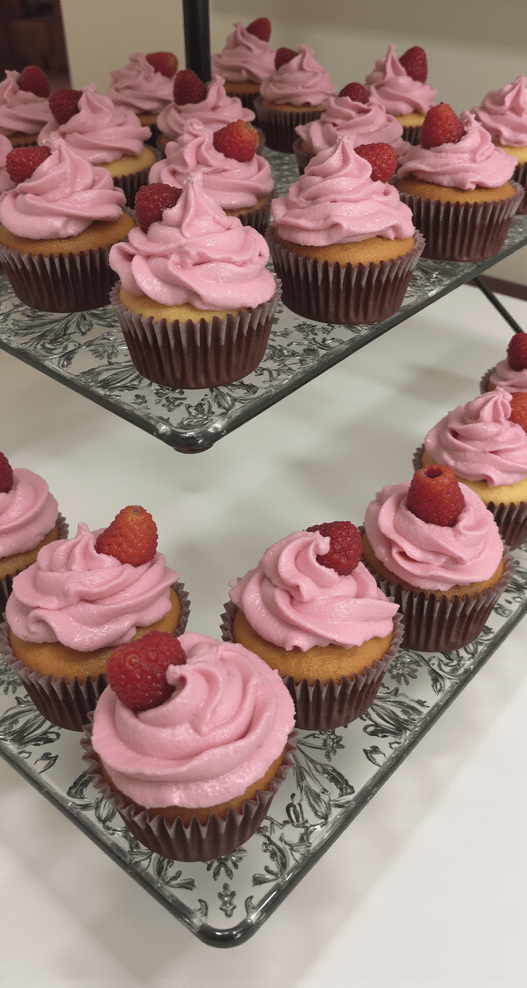 A beautifully arranged display of frosted berry cupcakes, featuring vibrant berry toppings and delicate swirls of frosting on a rustic wooden table.