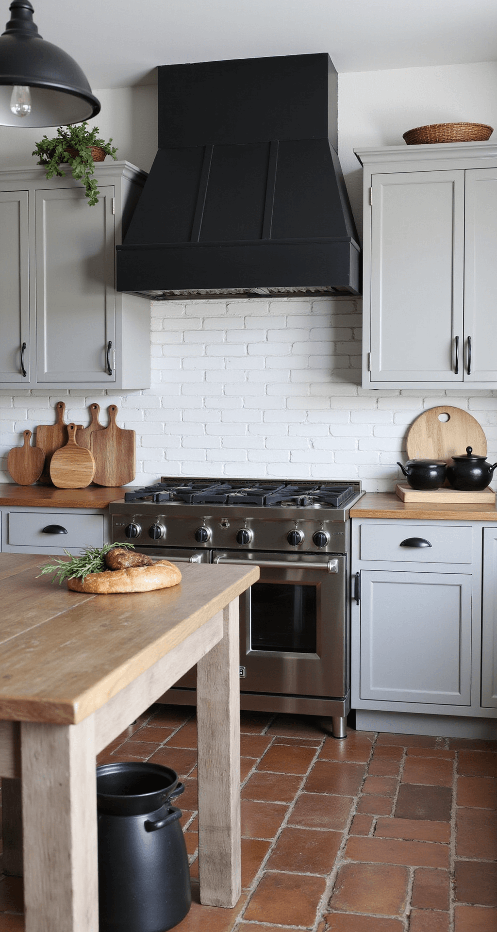 Modern farmhouse kitchen featuring medium castle grey Shaker cabinets with matte black hardware, a dramatic black range hood, a weathered wood island, industrial black pendant lights, and reclaimed brick flooring, styled with vintage breadboards, black stoneware, and dried herbs.